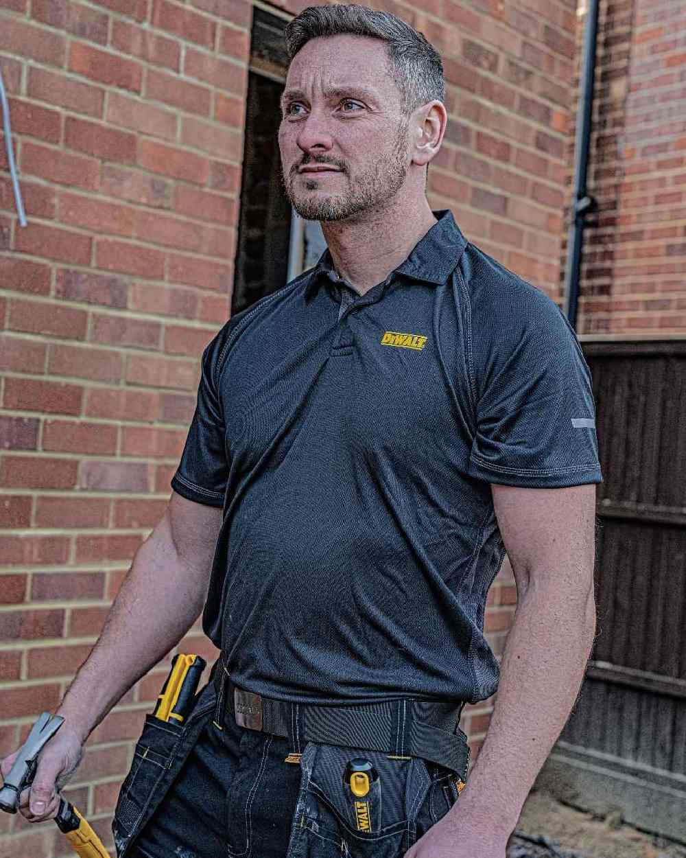 Black Coloured DeWalt Rutland Performance Polo Shirt on outdoor background