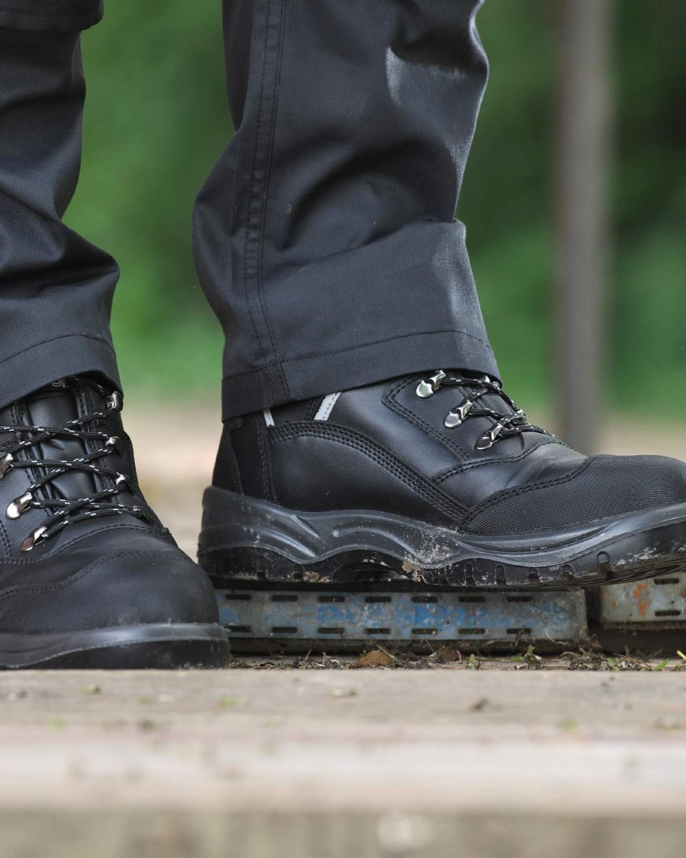 Black coloured Fort Knox Safety Boots on blurry green background