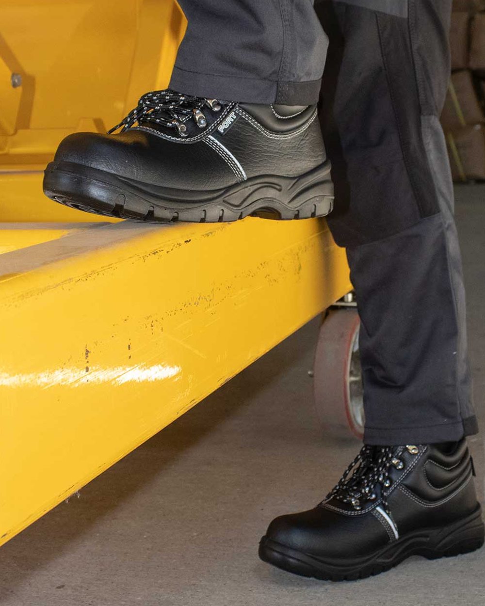 Black coloured Fort Workforce Safety Boots on yellow background
