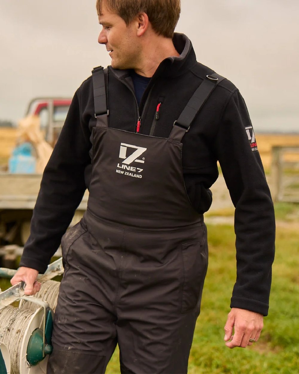 Black Coloured Line 7 Mens Territory Storm Pro20 Waterproof Bib Overtrouser on farm background