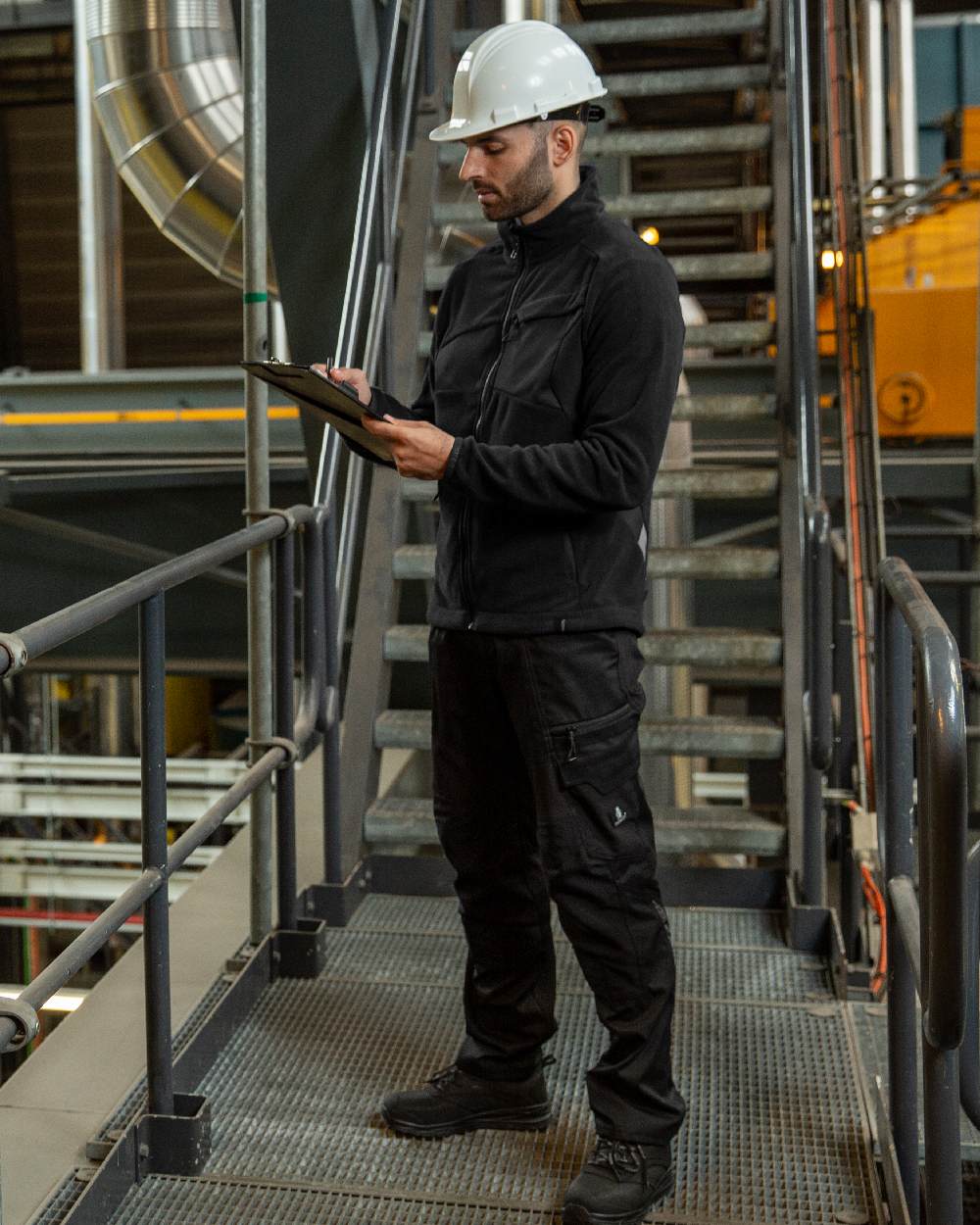 Black Coloured Mascot Workwear Mens Accelerate Stretch Zones Trousers on construction background