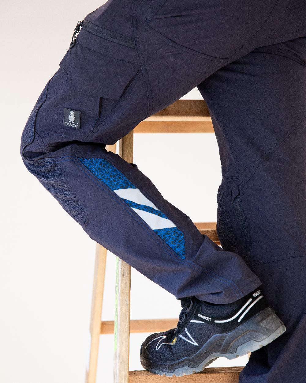 Dark Navy Coloured Mascot Workwear Mens Accelerate Ultimate Stretch Trousers With Kneepad Pockets on construction background