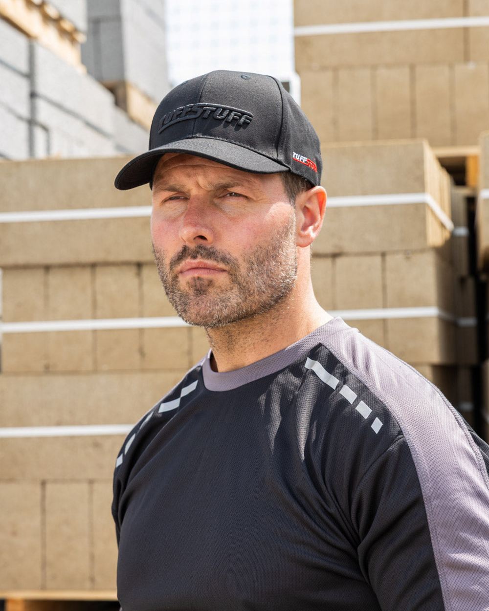 Black coloured TuffStuff Baseball Cap on construction background