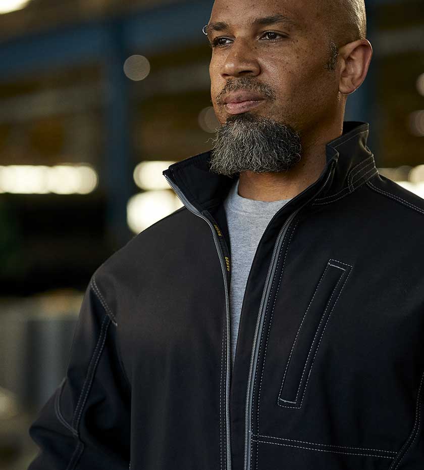 Warehouse Workwear - Man wearing Black Softshell jacket. Work Clothing for indoor warehouse operatives.