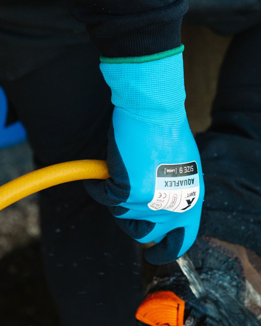 Blue Black coloured Xpert Core Aquaflex Waterproof Fully Coated Gloves on blurry background