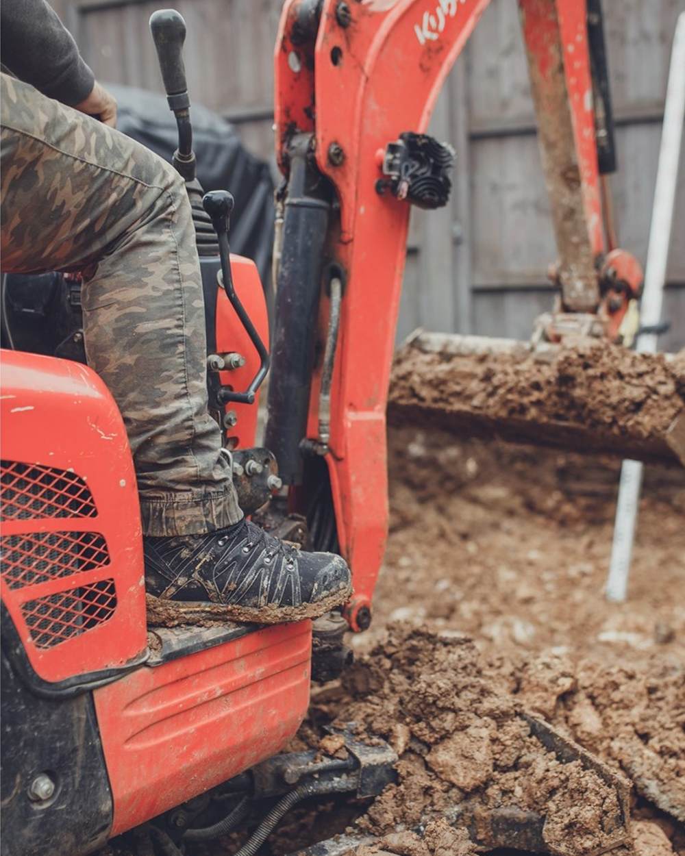 Black Coloured Amblers Safety AS254 Safety Boots on a muddy background