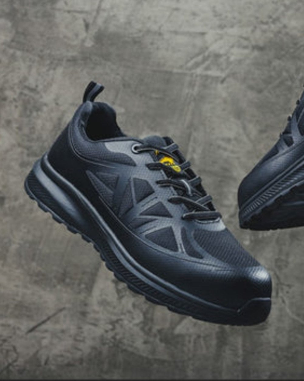 Black Coloured Amblers Safety AS721C Hurdle S1PL Safety Trainers on Stone Background