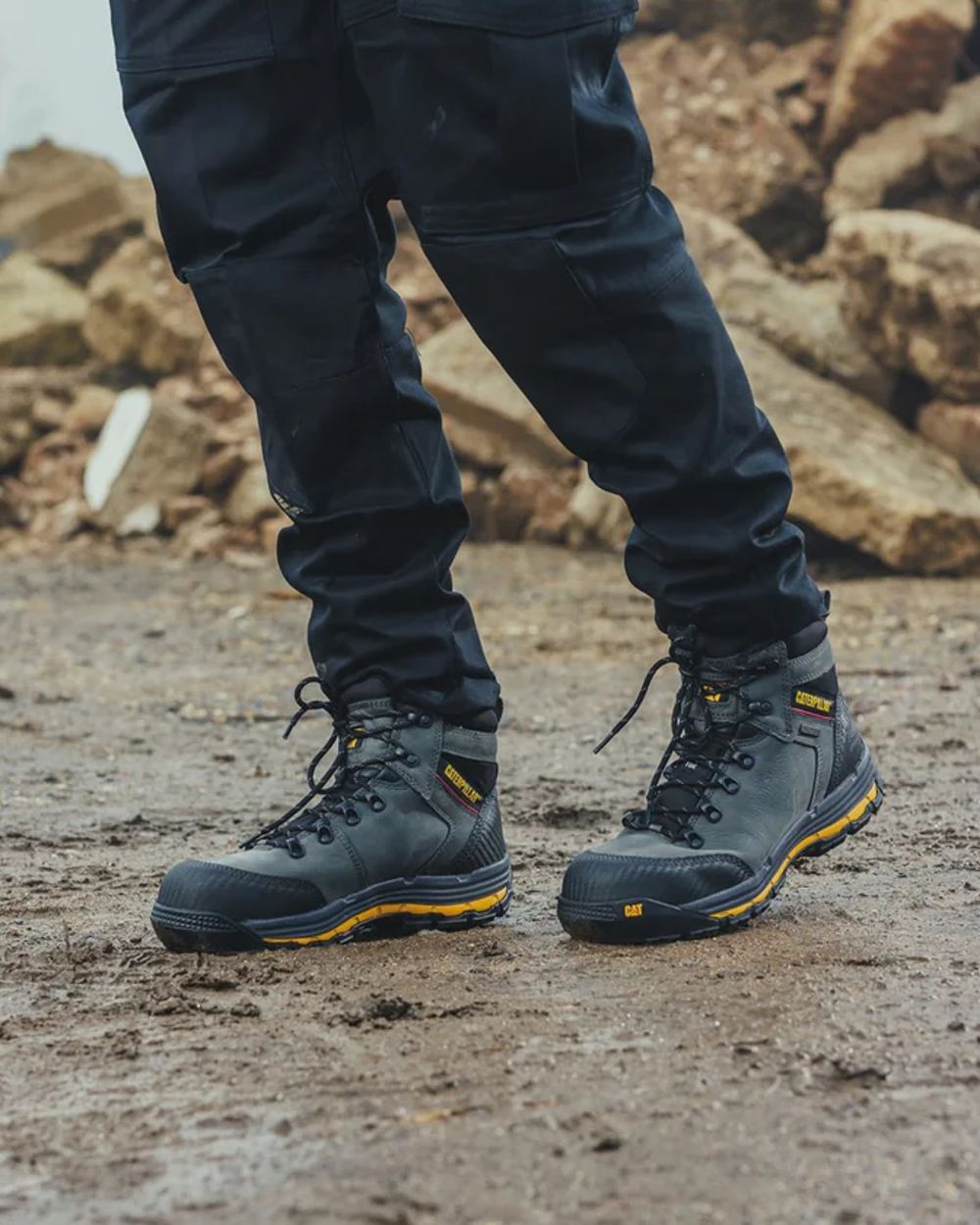 Dark Shadow Coloured Caterpillar Munising Safety Boot On A Muddy Background