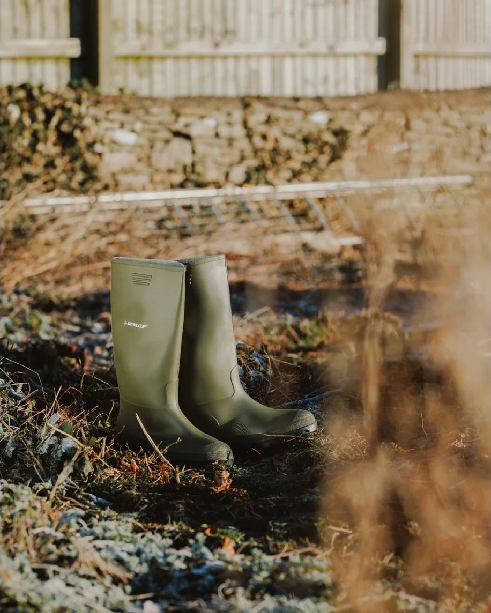 Green coloured Dunlop Pricemastor Wellingtons on blurry background