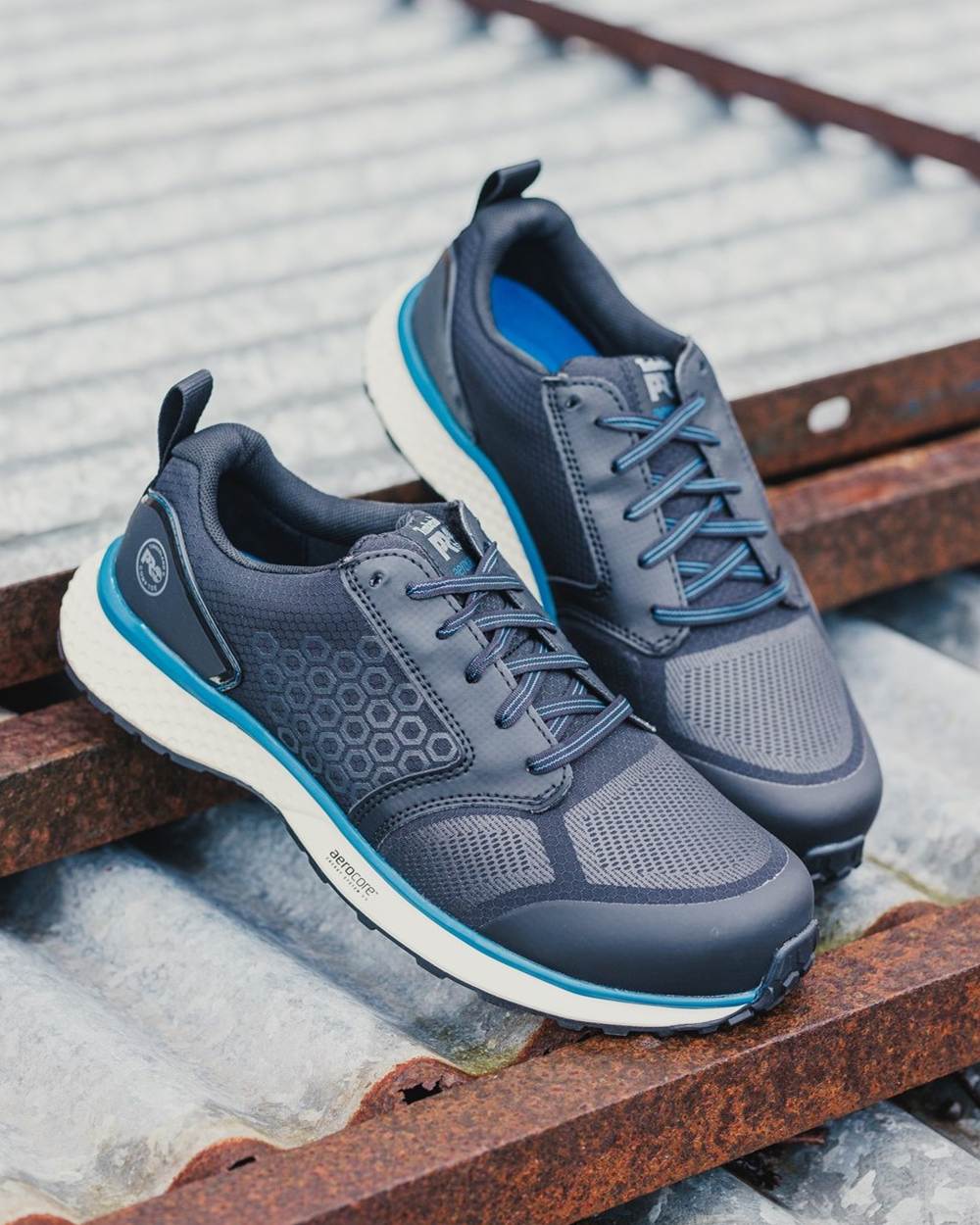Black/Blue coloured Timberland Pro Reaxion Composite Safety Trainers on grey roof background