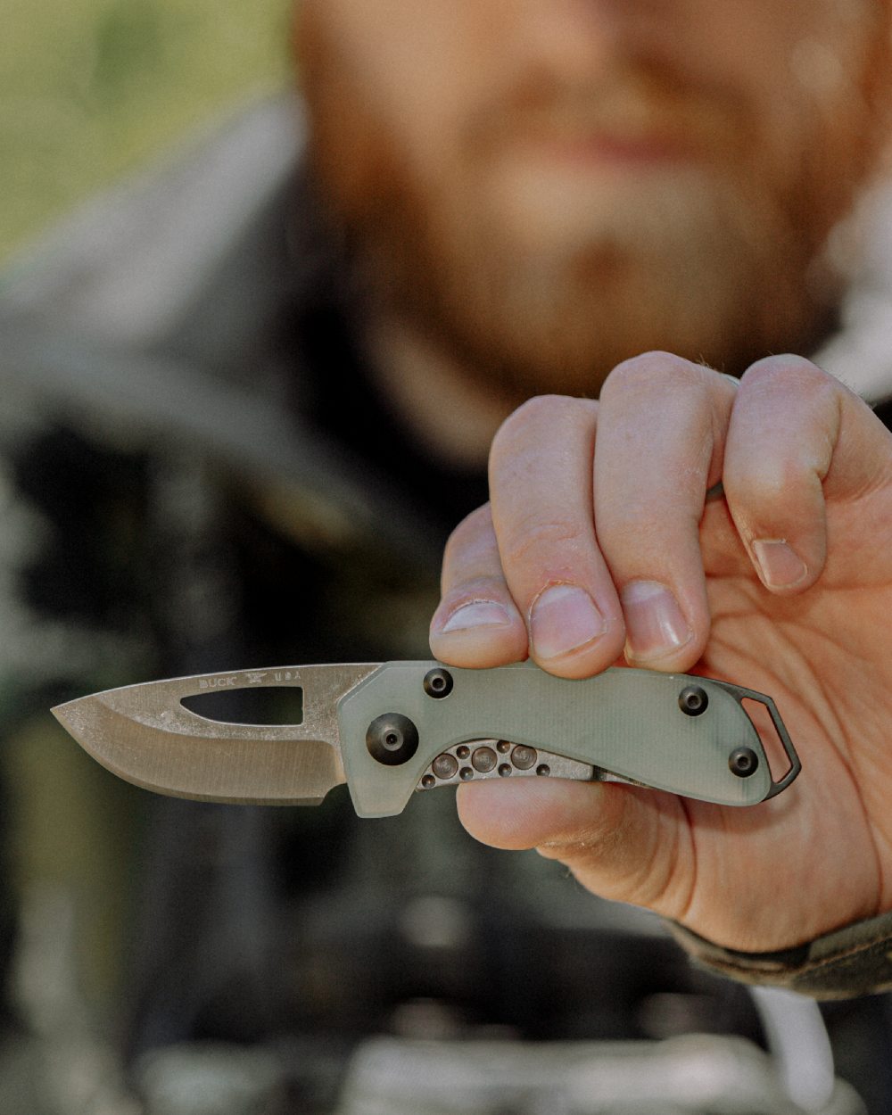 Natural coloured Buck Budgie Knife on blurry background 