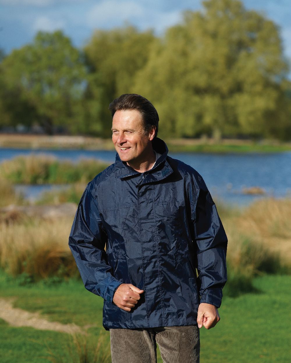 Navy coloured Champion Typhoon Waterproof Shell Jacket on grass background 