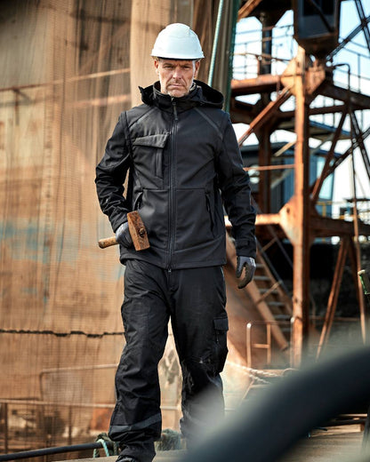 Black Coloured Elka Mens Working Xtreme Softshell Jacket With Detachable Sleeves on construction background 