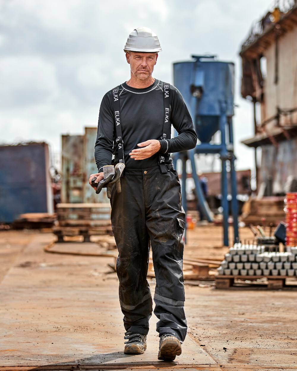 Black Coloured Elka Mens Working Xtreme Stretch Combi Trousers on construction background 