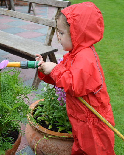 Red coloured Fort Childrens Splashaway Rainsuit on green background 