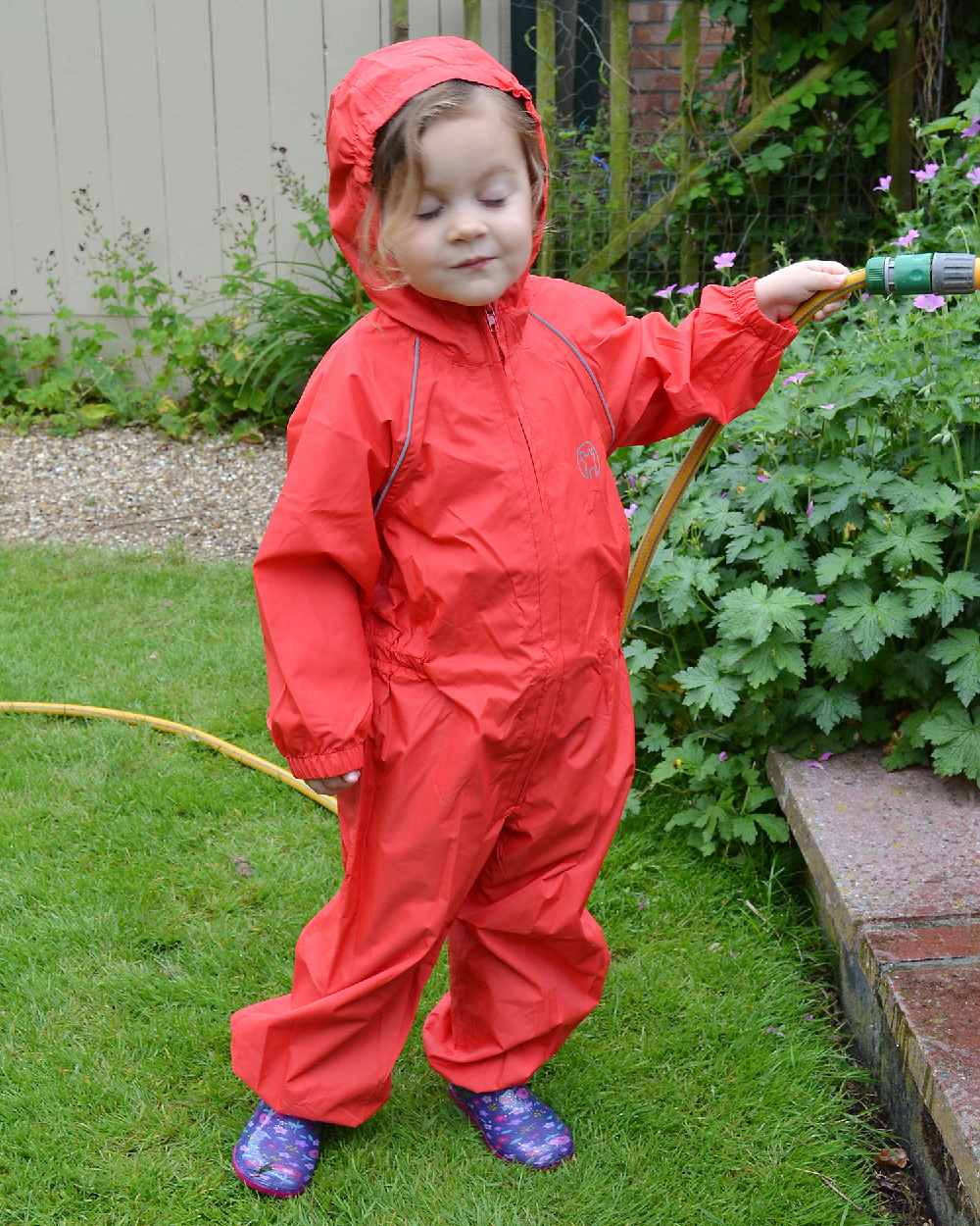 Red coloured Fort Childrens Splashaway Rainsuit on green background 