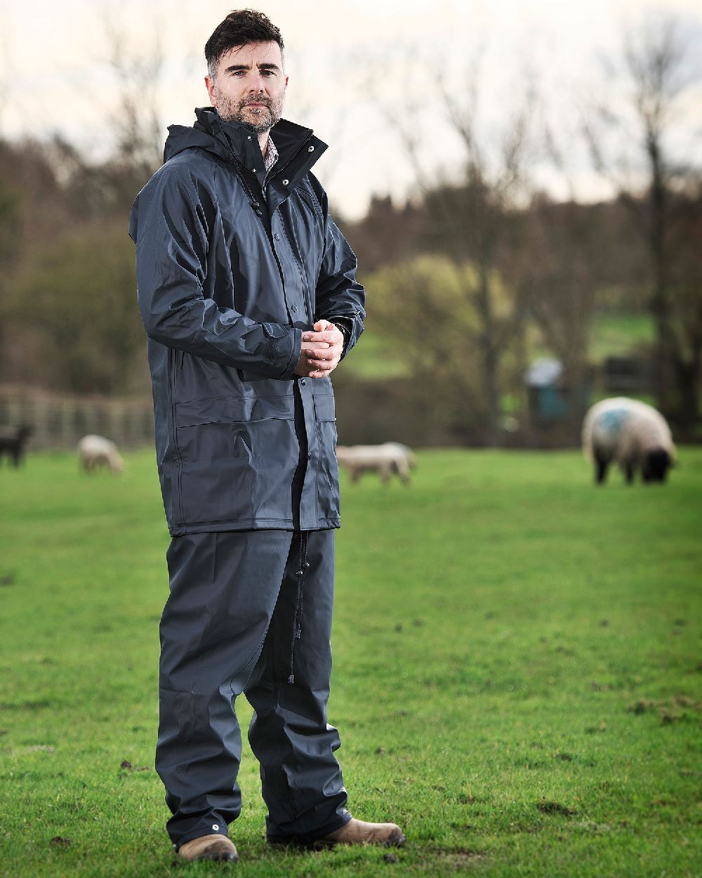 Navy coloured Fort Fortex Flex Waterproof Trousers on blurry green background 