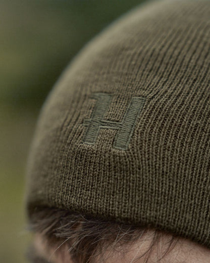 Willow Green Orange Coloured Harkila Reversible Beanie on outdoor background 
