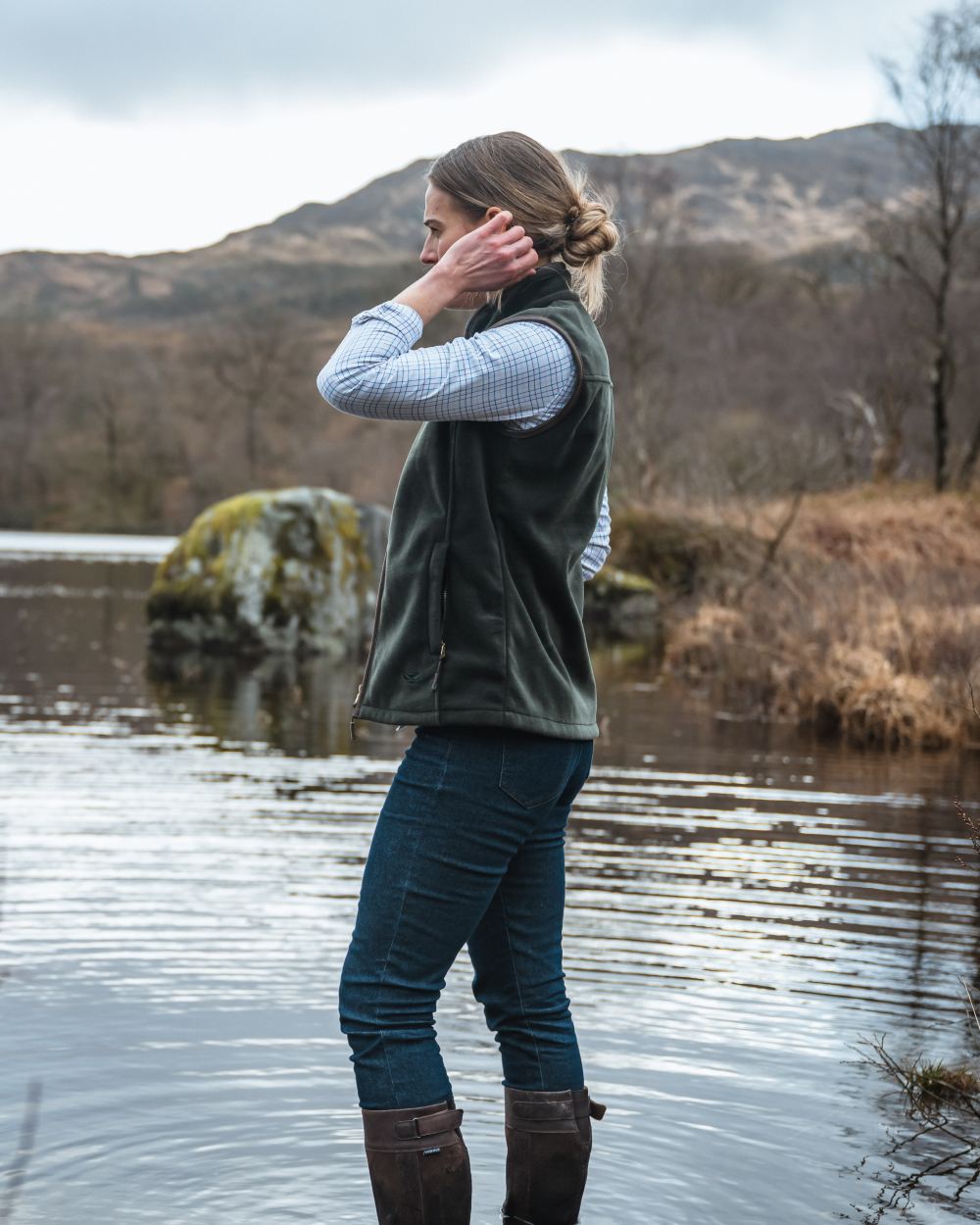 Pine Green Coloured Hoggs of Fife Stenton Ladies Fleece Gilet on lake background 