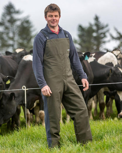 Olive coloured Kaiwaka Mens Stormforce Bib Overtrousers on grassy background 