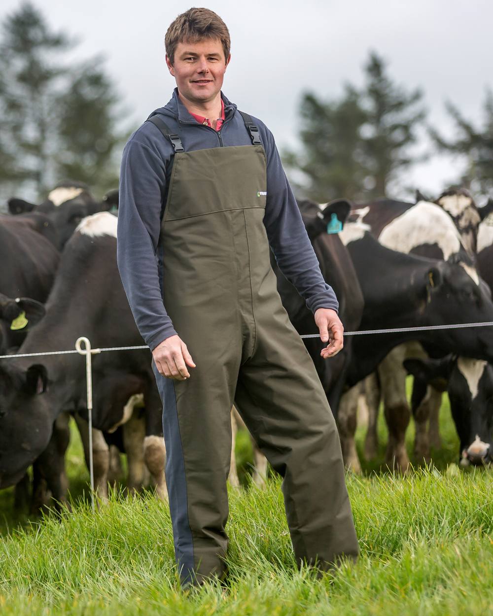 Olive coloured Kaiwaka Mens Stormforce Bib Overtrousers on farm background 