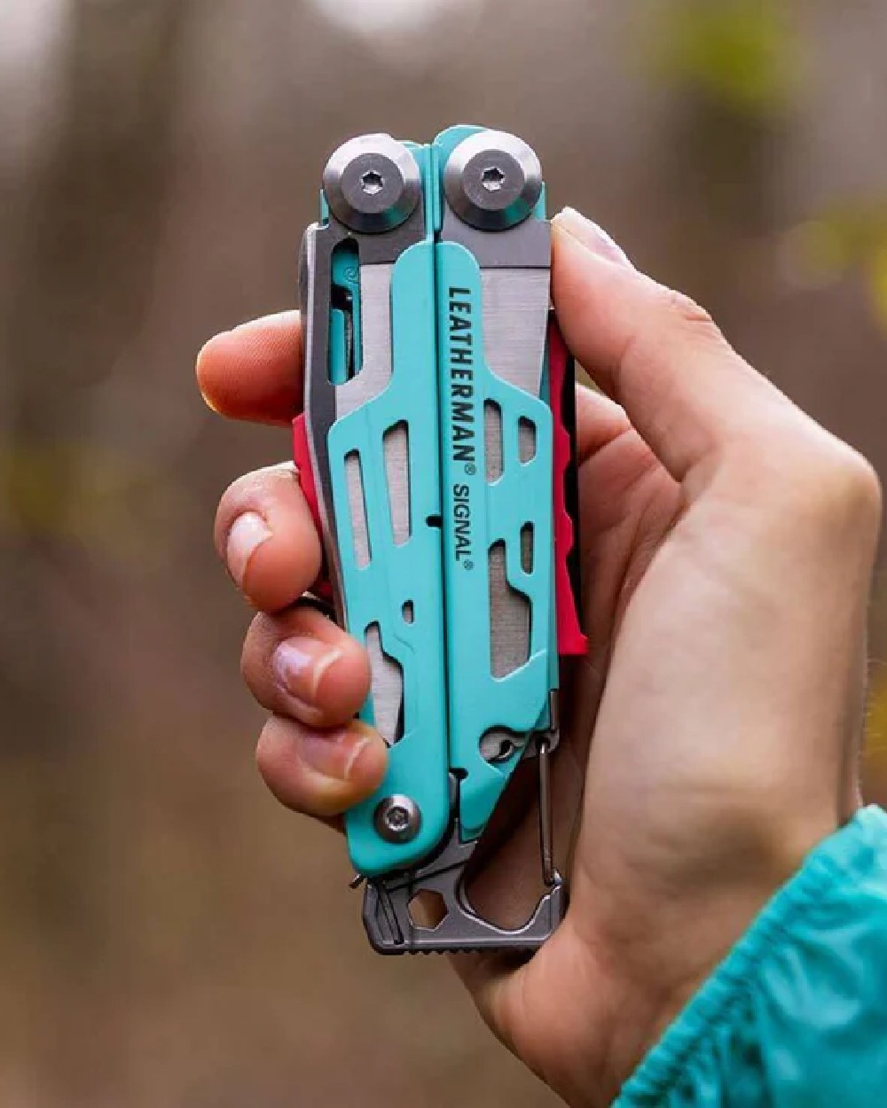 Aqua Coloured Leatherman Signal+ Multi-Tool W/ Nylon Sheath On A blurry Background 