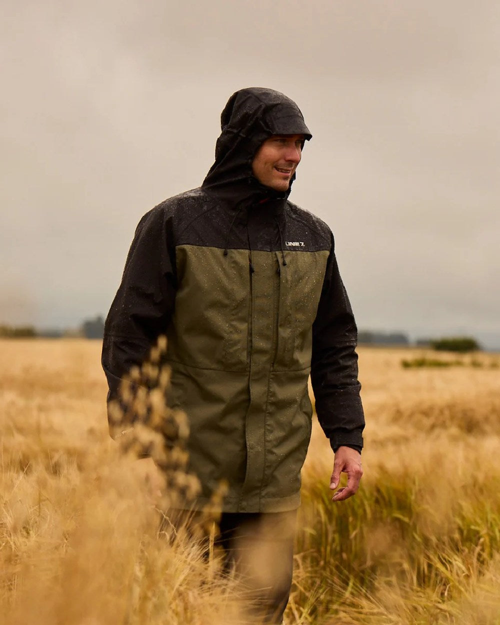 Moss Black Coloured Line 7 Mens Territory Storm Pro20 Waterproof Jacket on farm background 