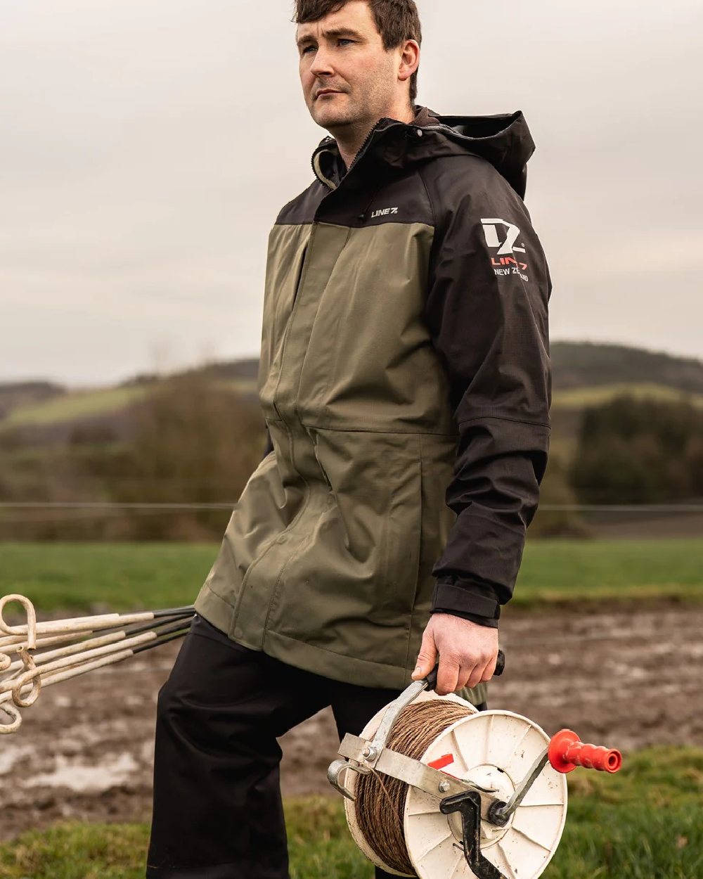 Moss Black Coloured Line 7 Mens Territory Storm Pro20 Waterproof Jacket on farm background 