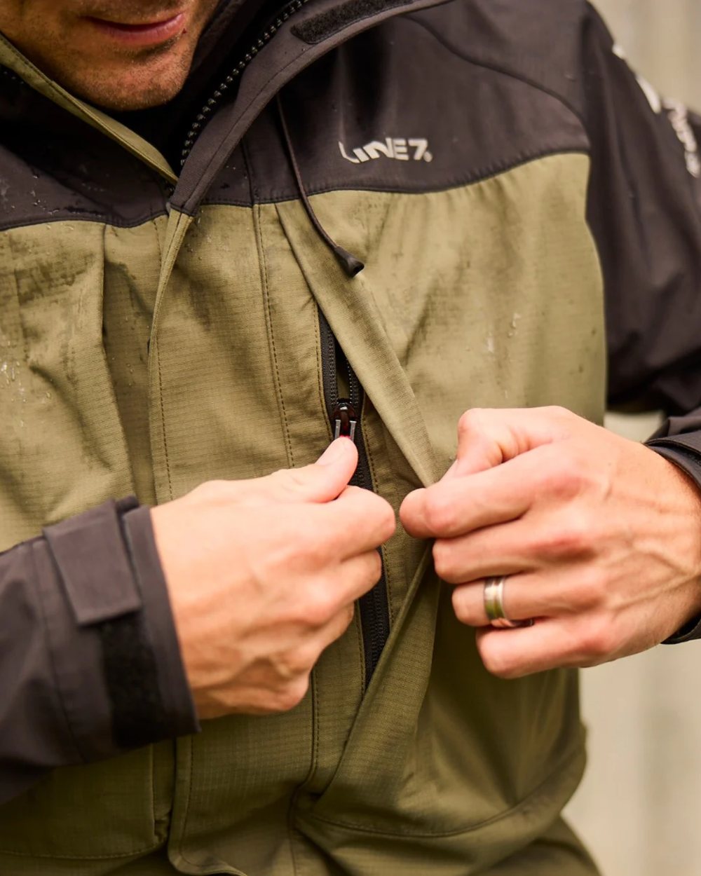 Moss Black Coloured Line 7 Mens Territory Storm Pro20 Waterproof Jacket on blurry background 