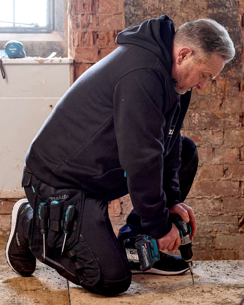 Black Coloured Makita Mens Onyx Stretch Trousers on construction background 