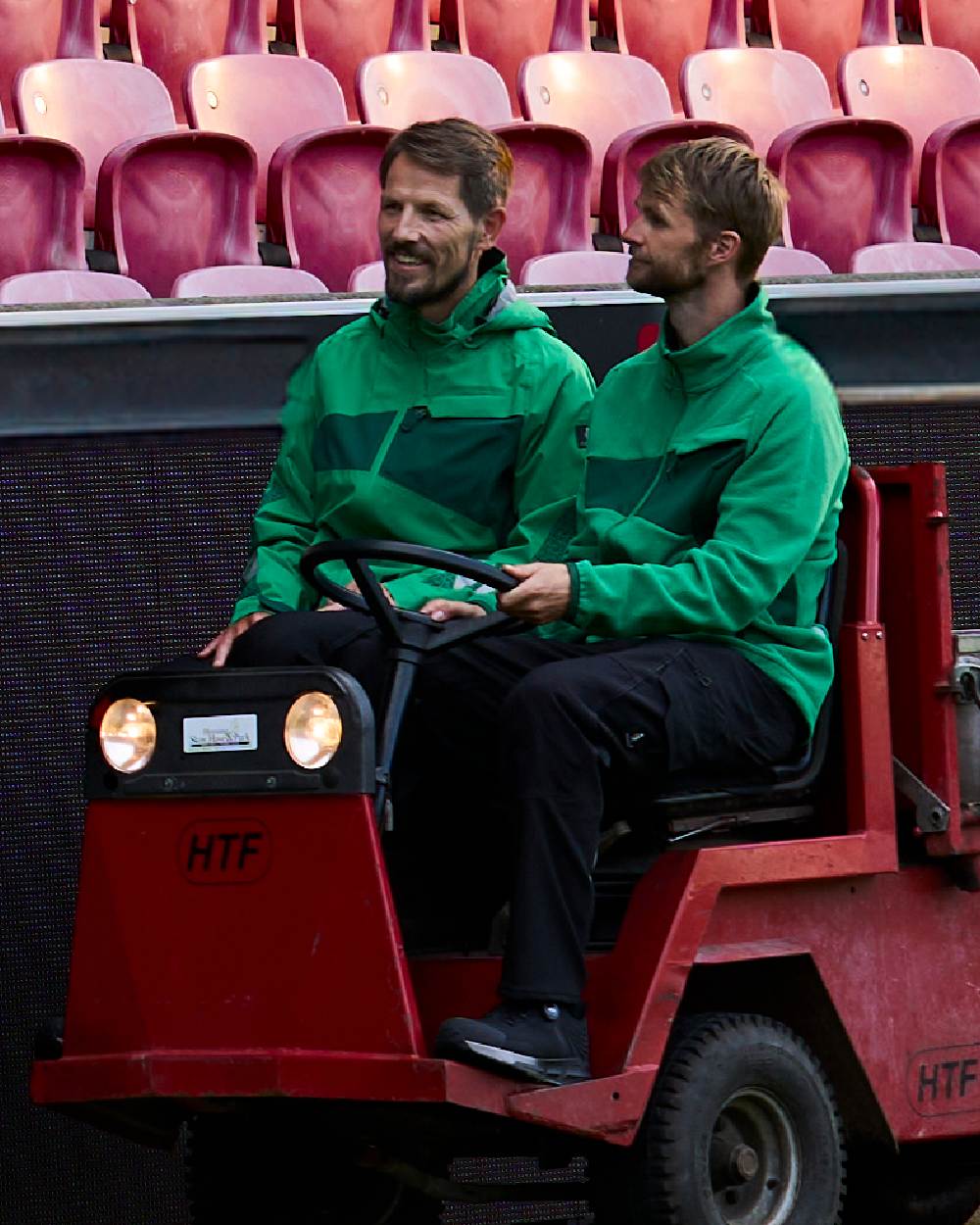 Grass Green Coloured Mascot Workwear Mens Accelerate Fleece Jacket on stadium background 