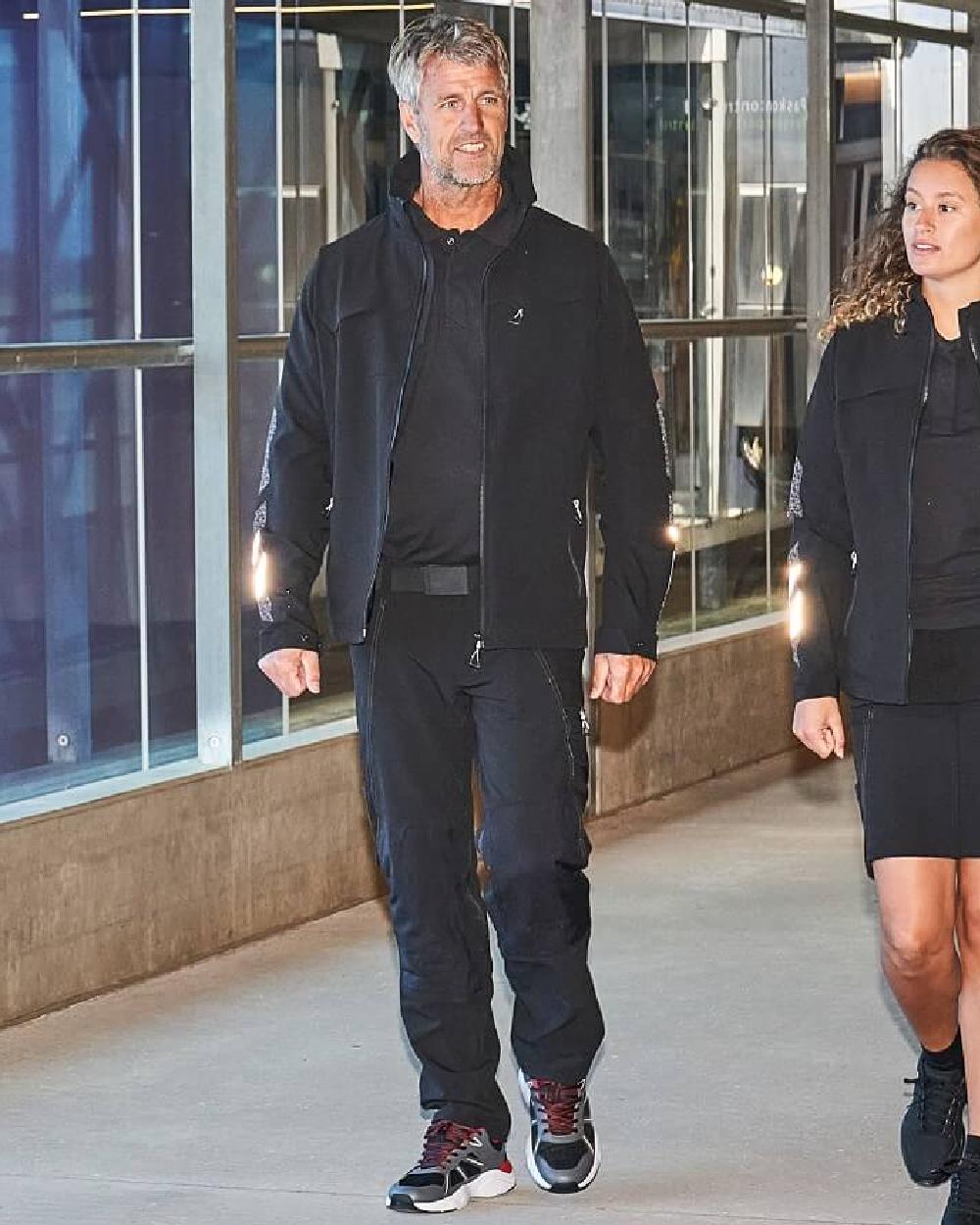 Black Coloured Mascot Workwear Mens Accelerate Lightweight Jacket on factory background 