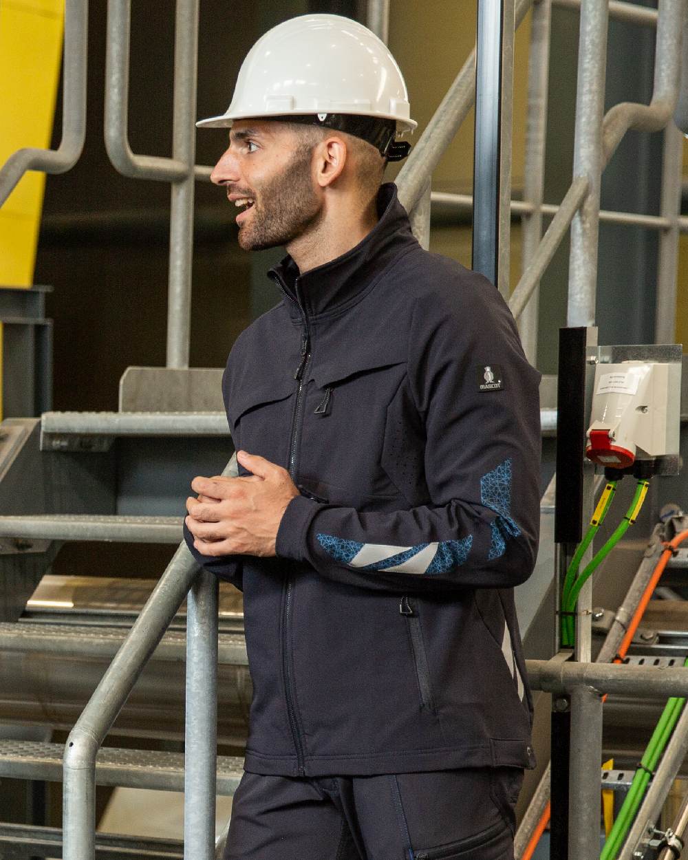 Dark Navy Coloured Mascot Workwear Mens Accelerate Lightweight Jacket on factory background 