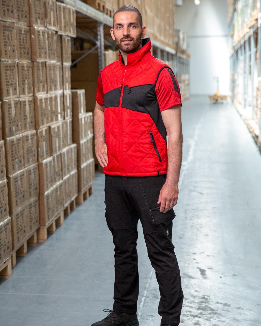 Traffic Red Black Coloured Mascot Workwear Mens Accelerate Lightweight Thermal Gilet on warehouse background 