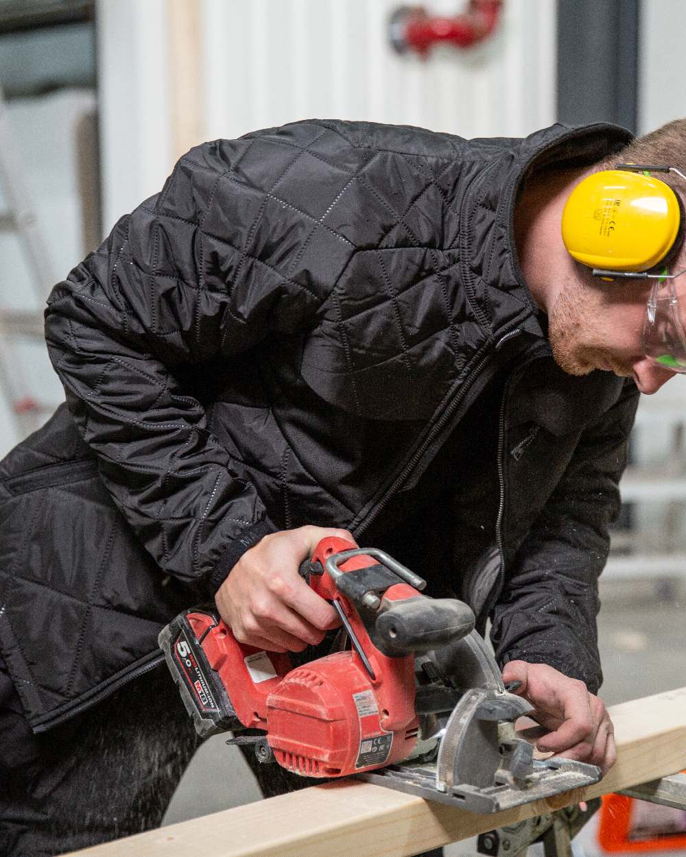 Black Coloured Mascot Workwear Mens Accelerate Lightweight Thermal Jacket on construction background 