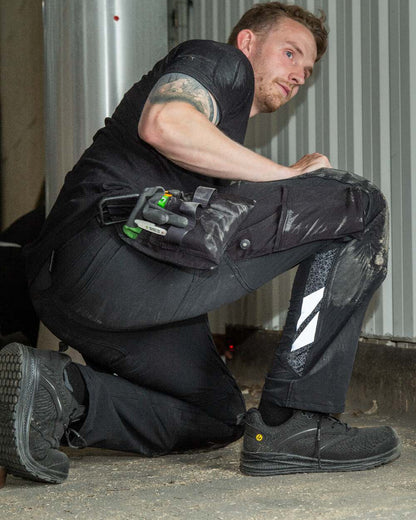 Black Coloured Mascot Workwear Mens Accelerate Lightweight Trousers With Holster Pockets on factory background 