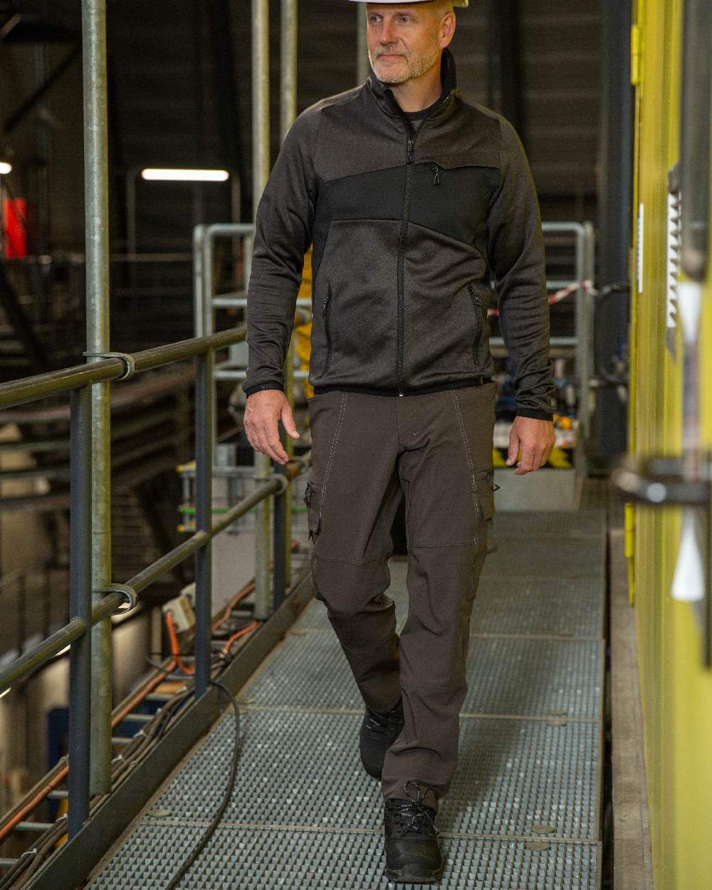 Dark Anthracite Coloured Mascot Workwear Mens Accelerate Lightweight Trousers With Thigh Pockets on factory background 