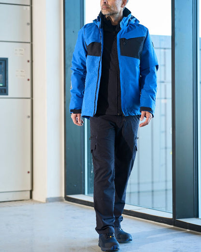 Dark Navy Coloured Mascot Workwear Mens Accelerate Lightweight Trousers With Thigh Pockets on factory background 