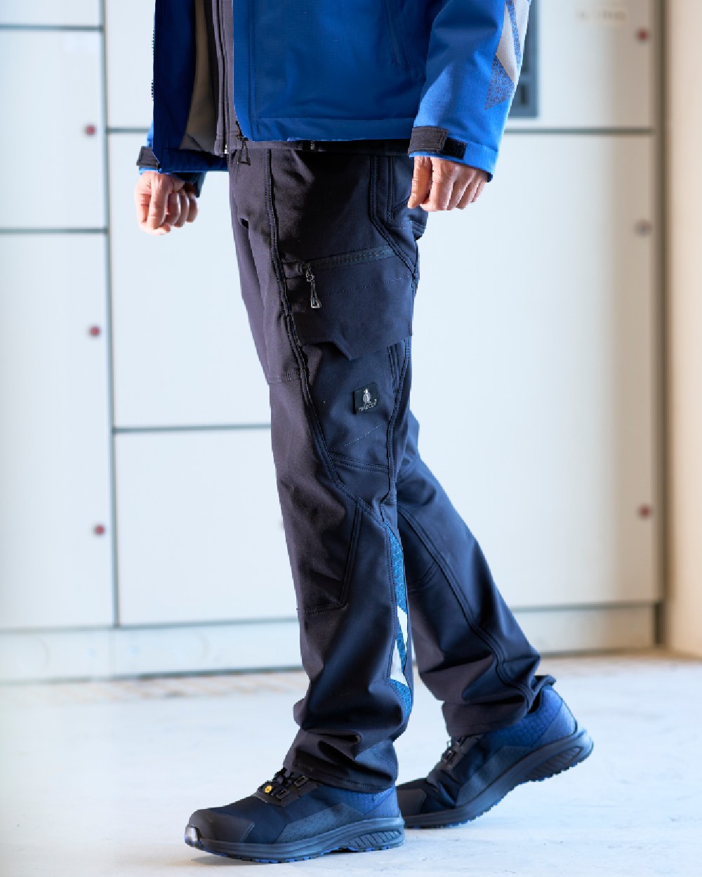 Dark Navy Coloured Mascot Workwear Mens Accelerate Lightweight Trousers With Thigh Pockets on factory background 
