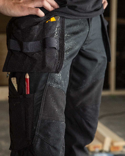Black Coloured Mascot Workwear Mens Accelerate Trousers With Holster Pockets on factory background 