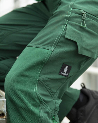 Green Coloured Mascot Workwear Mens Accelerate Ultimate Stretch Lightweight Trousers on farm background 