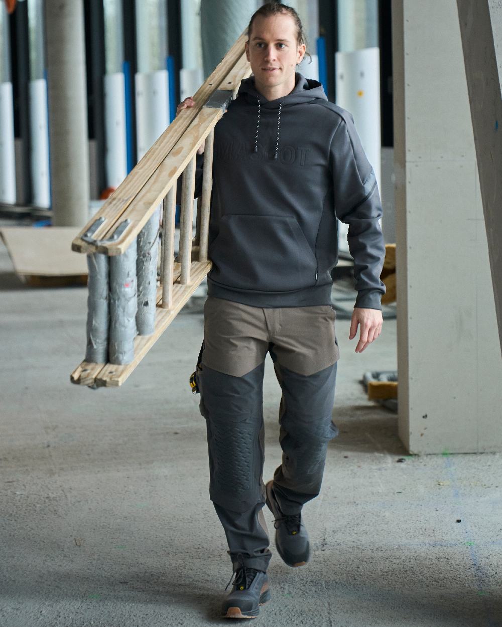 Dark Sand Stone Grey Coloured Mascot Workwear Mens Customized Ultimate Stretch Trousers on construction background 
