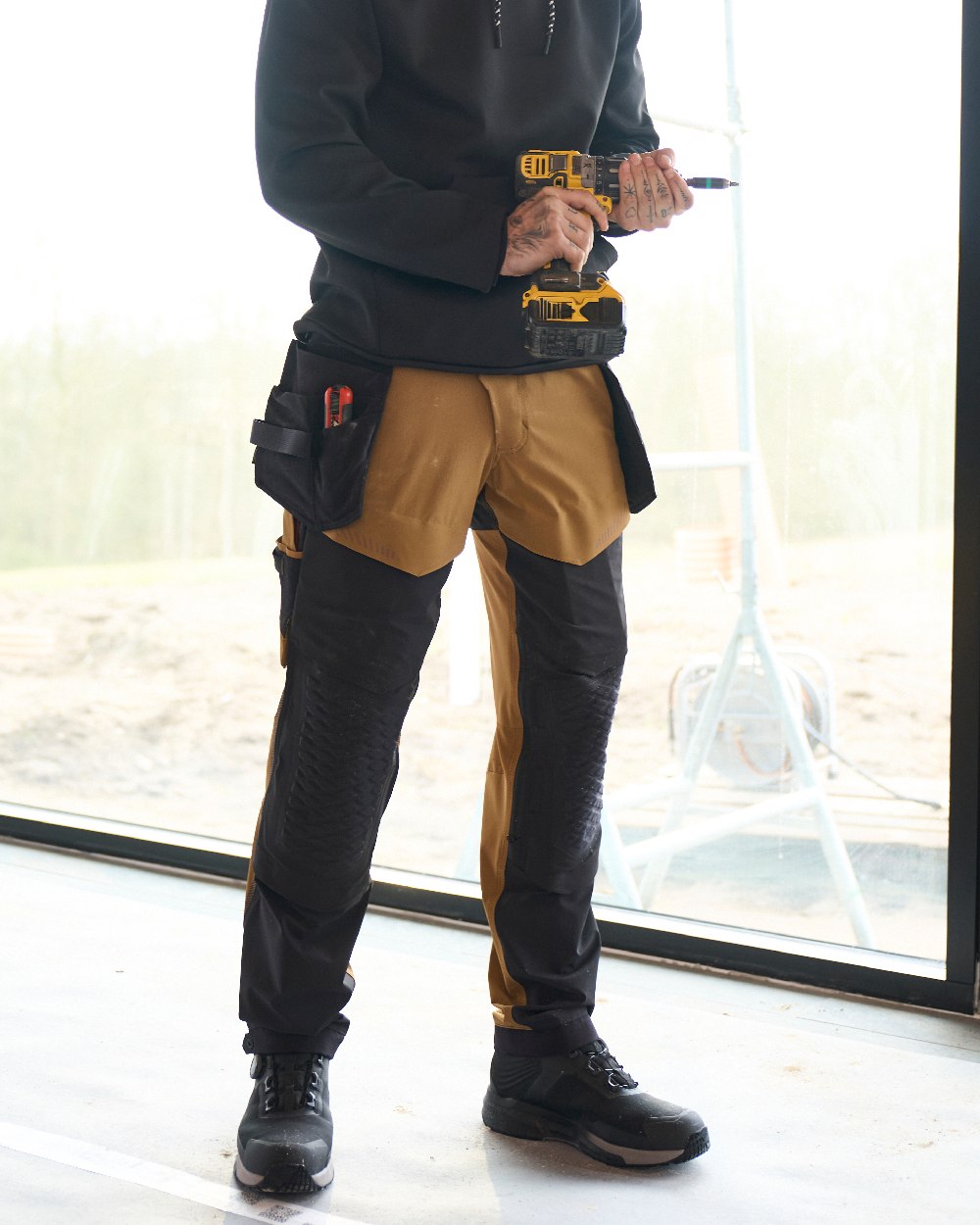 Nut Brown Black Coloured Mascot Workwear Mens Customized Ultimate Stretch Trousers on construction background 