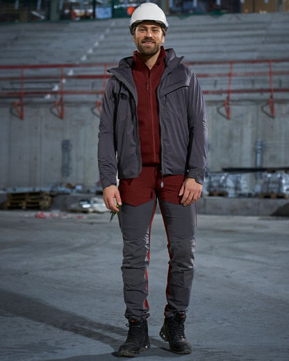 Bordeaux Stone Grey Coloured Mascot Workwear Mens Customized Ultimate Stretch Trousers With Kneepad Pockets on construction background 