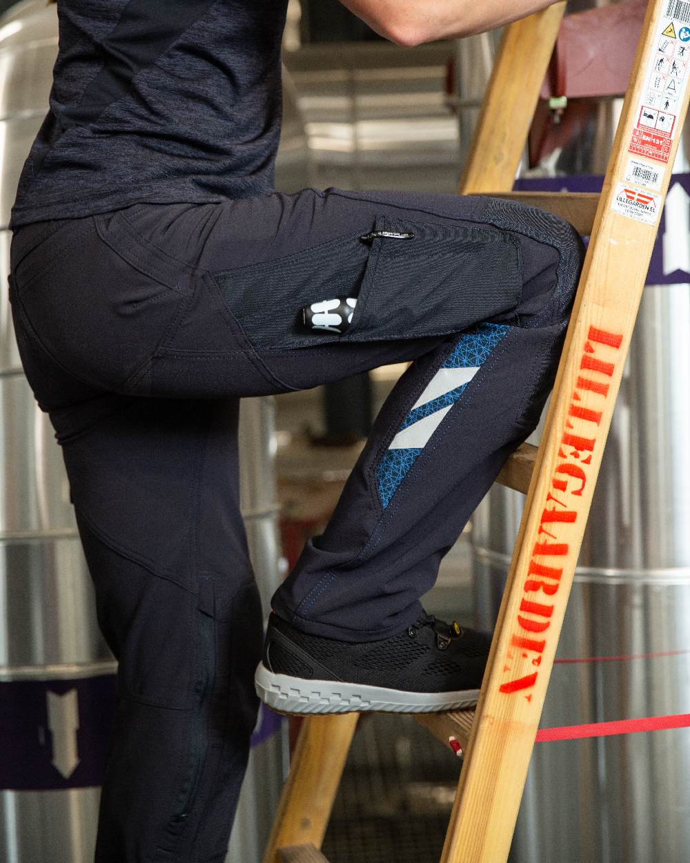 Dark Navy Coloured Mascot Workwear Womens Accelerate Lightweight Trousers With Kneepad Pockets on factory background 