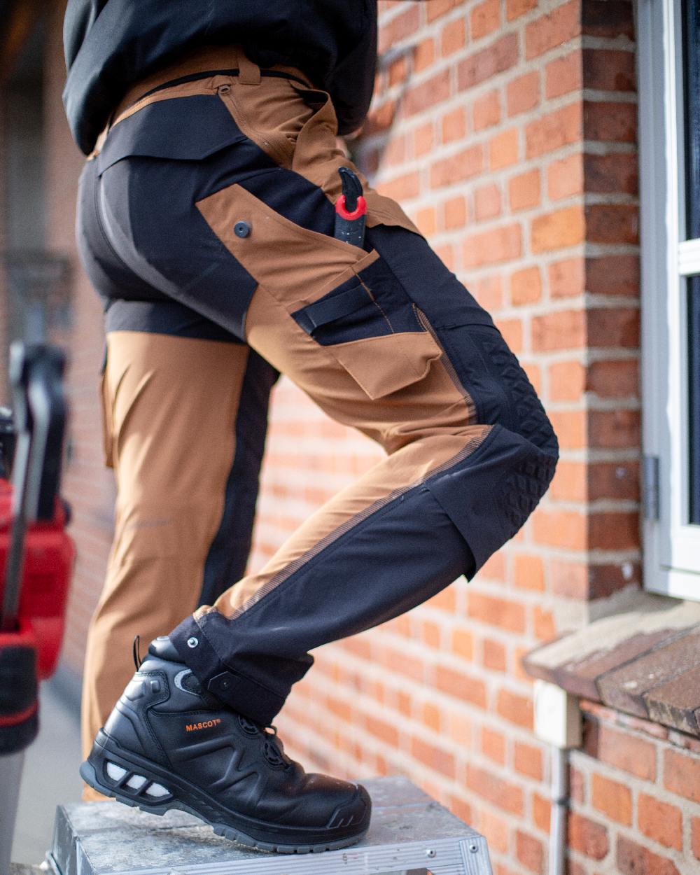 Nut Brown Black Coloured Mascot Workwear Womens Customized Diamond Fit Trousers With Kneepad Pockets on outdoor background 