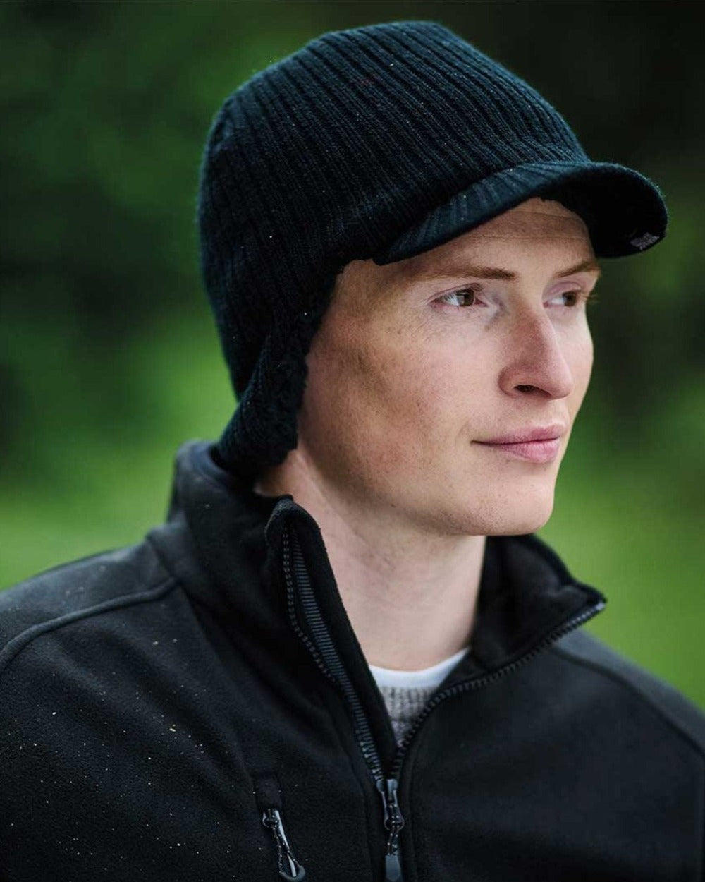 Black coloured Regatta Anvil Knitted Peak Cap on blurry green background