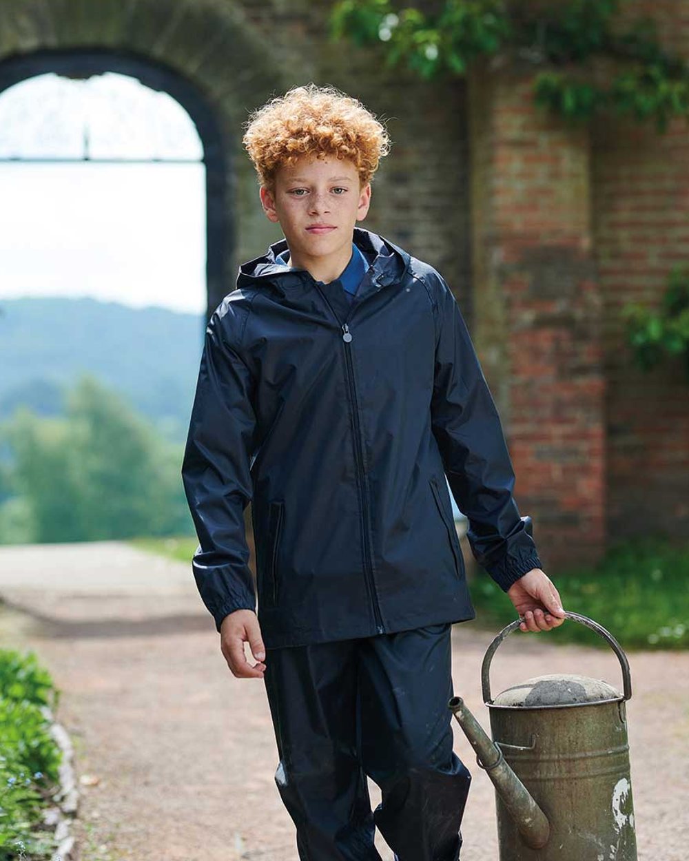 Navy coloured Regatta Kids Pro Stormbreak Waterproof Overtrousers on brick wall background