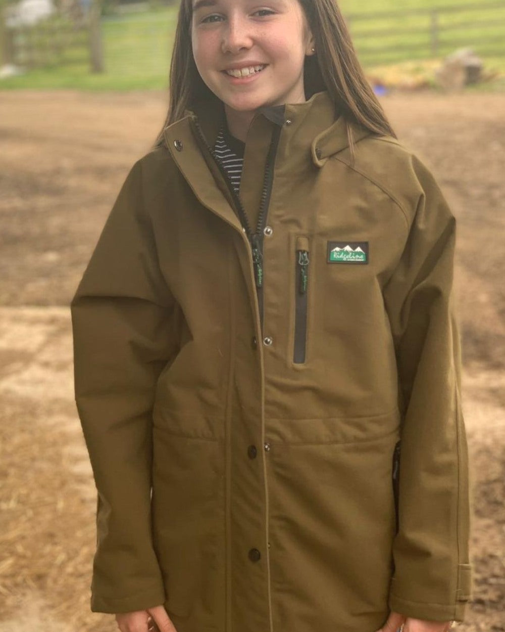 Teak coloured Ridgeline Kids Monsoon Classic Jacket on farm background 