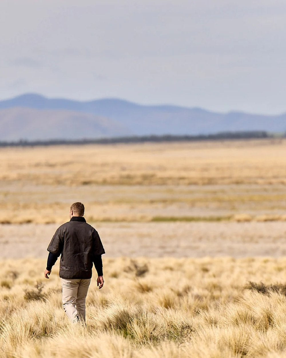 Brown Coloured Swanndri Mens 3/4 Sleeve Oilskin Jacket on field background 